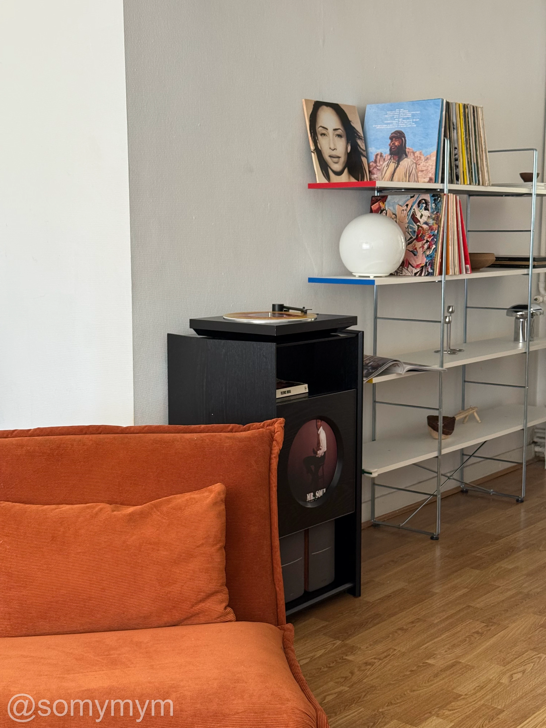 A record stand behind an orange lounge chair